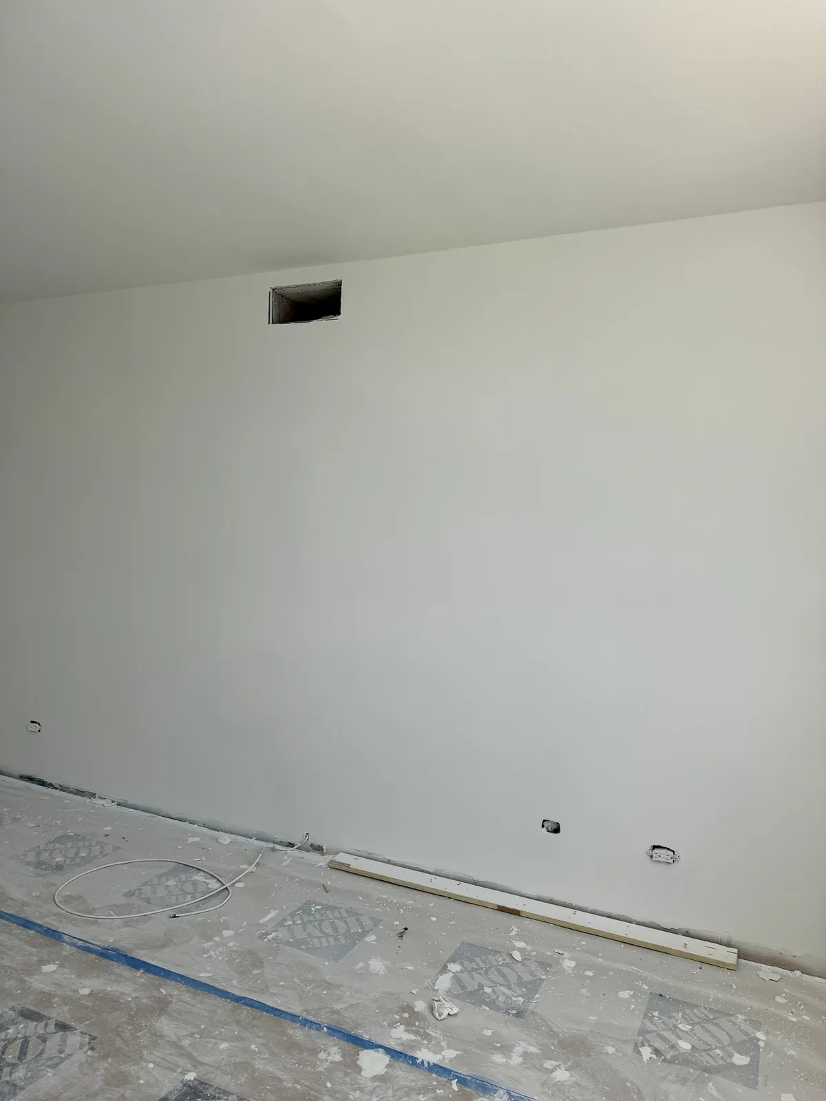 Same wall after wallpaper removal and drywall repair, smooth and primed